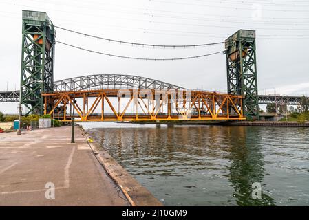 Ponte verticale su un canale che conduce ad un porto. Un viadotto autostradale è sullo sfondo. Foto Stock