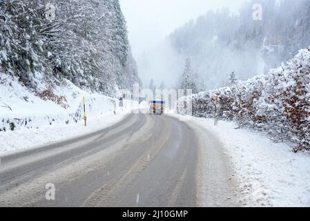 Autocisterna carburante su una strada di montagna innevata durante le nevicate pesanti in inverno Foto Stock