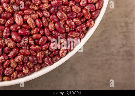 La foto mostra fagioli rossi. La consistenza dei semi è fatta in HD ad alta risoluzione. Lo sfondo dei chicchi è marrone. I fagioli sono rossi e rosa. Foto Stock