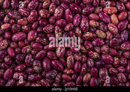 La foto mostra fagioli rossi. La consistenza dei semi è fatta in HD ad alta risoluzione. Lo sfondo dei chicchi è marrone. I fagioli sono rossi e rosa. Foto Stock