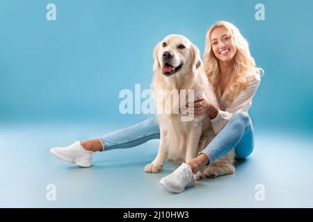Giovane donna in posa con il suo cane allo studio blu Foto Stock