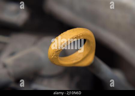 Primo piano della maniglia gialla dell'astina di livello olio motore sotto il cofano della vettura. Messa a fuoco selettiva. Riparazione e manutenzione dell'auto Foto Stock