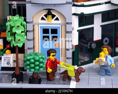 Tambov, Federazione Russa - 08 gennaio 2022 una minifcifra uomo per non vedenti Lego con un cane guida che cammina su una strada della città con una madre Lego wit Foto Stock