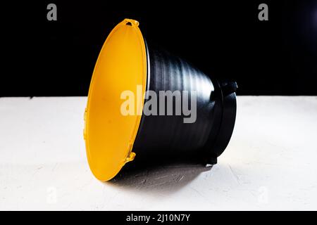 Riflettore standard con diffusore giallo opaco su sfondo nero. Attacco per flash studio con supporto bowens. Foto Stock