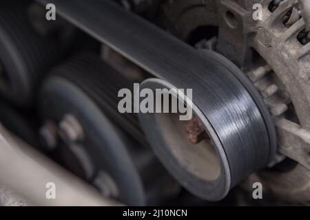 Primo piano della cinghia di trasmissione e del rullo dell'alternatore nel motore dell'auto. Motore sporco Foto Stock