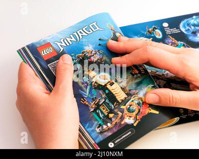 Tambov, Russia - 21 dicembre 2021 Woman browsing il catalogo Lego su una pagina con set Lego Ninjago. Foto Stock