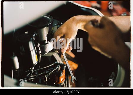 Meccanico a mano con una chiave che lavora su un motore vintage Foto Stock