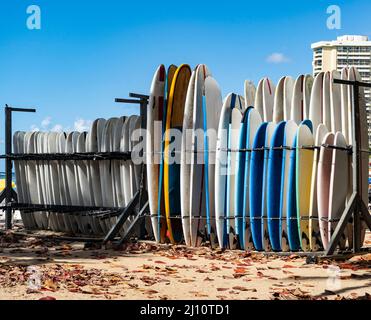 Tavole da surf multicolore in piedi su una rastrelliera su una spiaggia Hawaiiana Foto Stock