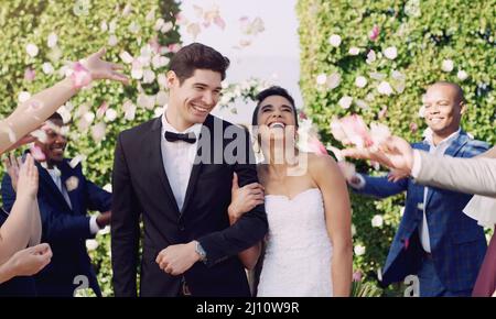 E ottengono essere felici alla fine. Corto colpo di una giovane coppia affettuosa newlywed che lascia il loro luogo di nozze con i loro ospiti che lanciano Foto Stock