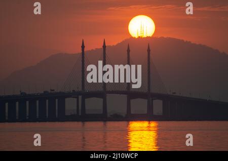 Mattina tuorlo d'uovo sorgere del sole sopra il Ponte di Penang e la collina di Tokkun. Foto Stock