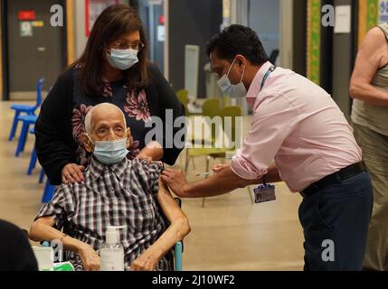 Devraj Jhalam, di 95 anni, accompagnato dalla figlia Dr. Lalitha Iyer, ha ricevuto il secondo colpo di richiamo del vaccino Covid-19 dal Dr. Nithya Nanda presso la clinica di vaccinazione del Salt Hill Activity Center di Slough, Berkshire. Il NHS in Inghilterra sta iniziando il lancio del Covid booster di primavera, con le persone che diventano eleggibili se hanno avuto il loro ultimo vaccino sei mesi fa. Data foto: Lunedì 21 marzo 2022. Foto Stock