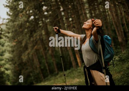 Bella giovane donna zaino in spalla godendo verde bella foresta intorno a lei Foto Stock