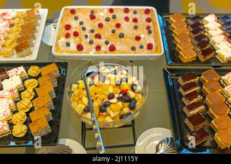 Macedonia di frutta e ampia selezione di dolci al tavolo a buffet Foto Stock