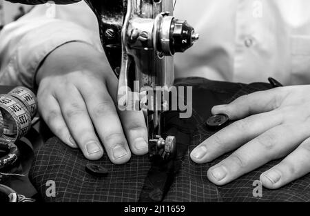 Tailor's hands close-up cucire abiti su una vecchia macchina da cucire retrò. Strumenti per un sarto, stilista di moda o marinaio Foto Stock