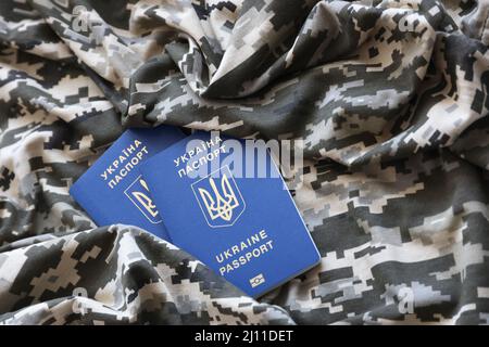 Passaporto straniero ucraino su tessuto con tessuto di camouflage pixed militare. Panno con motivo camo in pixel grigio, marrone e verde e Regno Unito Foto Stock