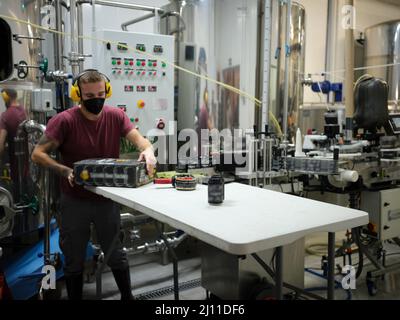 Lavoratore che confezionano lattine di birra su una rastrelliera di cartone in una fabbrica di imballaggio. Foto Stock