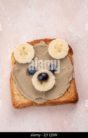 I bambini allegri sopportano toast con i butters di noci per la prima colazione Foto Stock