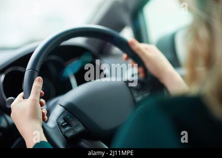 Viaggio lungo. Scatto di una donna che tiene il volante durante la guida. Foto Stock