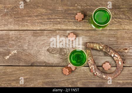 Concetto di giorno di San Patrizio. Cocktail verde tradizionale, cioccolato dolce a forma di foglie di trifoglio, ferro di cavallo, corda d'epoca. Festa tradizionale dicembre Foto Stock