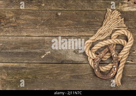 Ferro di cavallo e corda d'epoca. Concetto di buona fortuna per il giorno di San Patrizio. Vecchio legno assi sfondo, vista dall'alto, piatto Foto Stock