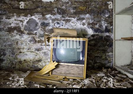 Una televisione retrò accanto al seminterrato di un edificio abbandonato. Foto Stock