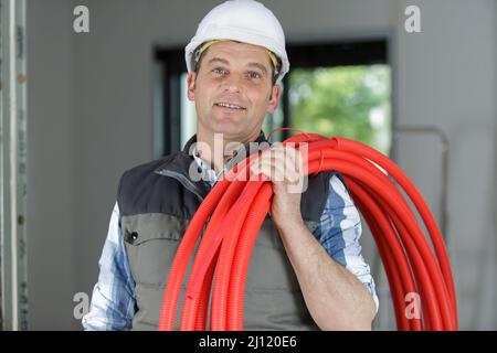 idraulico sorridente che tiene tubi rossi Foto Stock