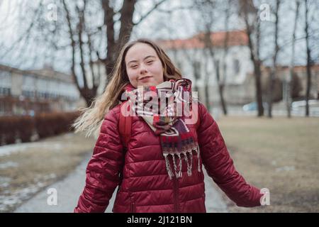 Giovane studentessa con sindrome di Down che cammina per strada in inverno Foto Stock