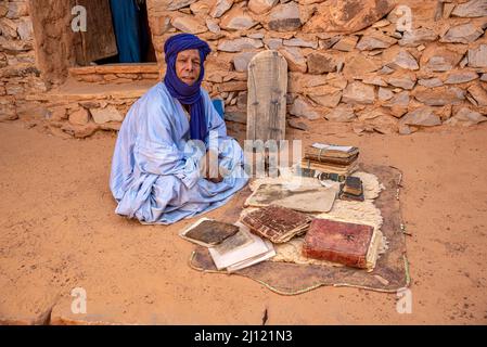 Uomo Mauritiano con boubou blu tradizionale e turbano e vecchi libri islamici in un'antica biblioteca, Chinguetti, Mauritania Foto Stock