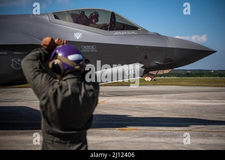 Un pilota dell'aeronautica degli Stati Uniti, 355th Squadron del combattente di Expeditionary, taxi in un F-35A che Lightning II dall'ala del combattente 354th, base dell'aeronautica di Eielson, Alaska come CPL del corpo marino degli Stati Uniti. Evan Goode, 3D Marine Logistics Group Motor Vehicle Operator, fornisce segnali manuali per l'arresto durante l'addestramento al rifornimento di hot pit presso la base aerea di Kadena, Giappone, 10 marzo 2022. La formazione congiunta contribuisce ad aumentare l'interoperabilità, dotando i servizi della capacità di lavorare in modo più efficiente come team in situazioni reali. (STATI UNITI Air Force foto di Airman 1st Classe Anna Nolte) Foto Stock