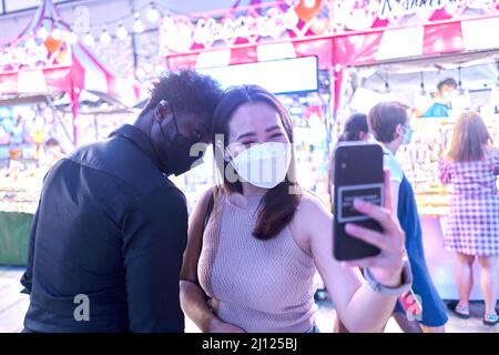 Amici multirazziali che prendono un selfie ad un mercato notturno di strada Foto Stock
