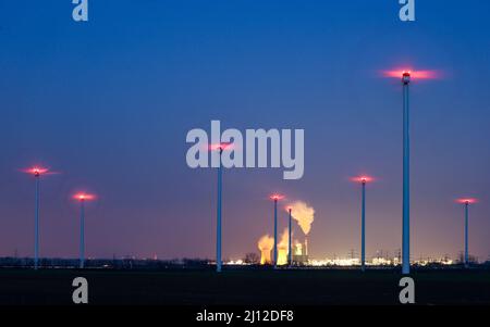 21 marzo 2022, Sassonia-Anhalt, Bad Lauchstädt: Il camino e le torri di raffreddamento della centrale elettrica a lignite di Schkopau stanno fumando dietro un parco eolico. I conflitti bellici stanno rianimando la discussione in Germania sulla graduale eliminazione della lignite e l’espansione delle energie rinnovabili. Foto: Jan Woitas/dpa-Zentralbild/dpa Foto Stock