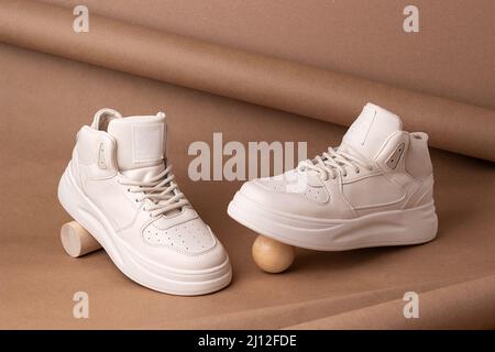 Scarpe ecologiche in pelle. Un paio di sneaker beige su sfondo marrone. Stile minimalista. Stile di vita sportivo informale. Foto Stock