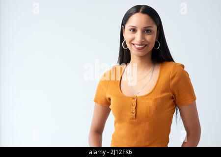 Sorridendo con sicurezza. Ritratto corto di una giovane donna attraente in piedi in studio su uno sfondo grigio. Foto Stock