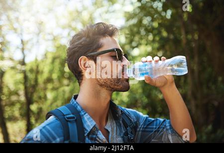 Rimani idratato durante la sua escursione. Scatto di un giovane che fa una sosta per un drink d'acqua mentre esplori l'aria aperta. Foto Stock