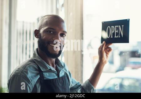 Sei pronto per il caos. Scatto di un bel giovane uomo in piedi e girare il cartello sulla porta del suo negozio di biciclette. Foto Stock