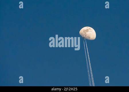 Aereo passeggeri che passa vicino alla luna bianca su uno sfondo blu cielo chiaro Foto Stock