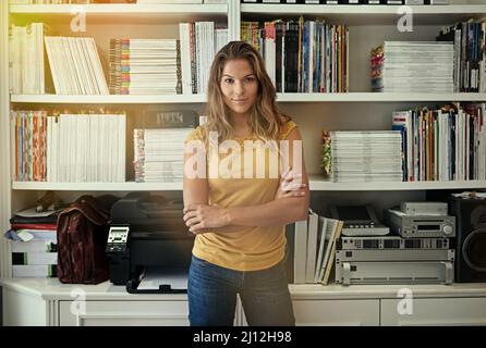 Scegli lo stile di vita che desideri. Ritratto di una donna in piedi di fronte a scaffali nel suo ufficio domestico. Foto Stock