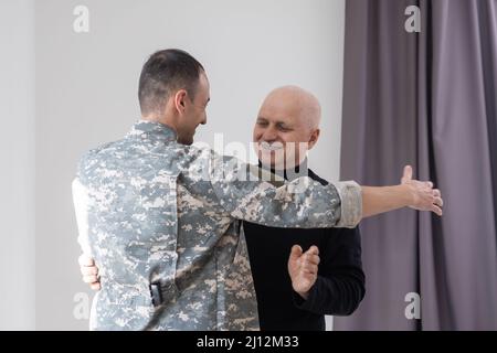 Il padre militare abbraccia suo figlio quando si riunì dopo una missione Foto Stock