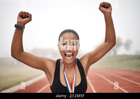 Feroce di fronte alle avversità. Scatto di una bella giovane atleta che festeggia alla fine della sua gara. Foto Stock