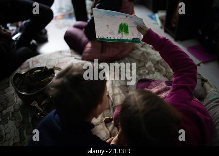 Oksana, la madre di Darina, 13 anni, e Arthur, 7 anni nei loro appartamenti al piano terra di un edificio in cui 20 persone vivono senza elettricità, acqua o gas. La famiglia è rifugiata dalla regione di Donbass, sono arrivati 2 anni fa ad Irpin per iniziare una nuova vita, non vogliono lasciare di nuovo la loro casa anche se c'è shelling tutto intorno a loro. Irpin centrale, come la città è sotto shelling durante l'invasione russa dell'Ucraina, il 11 marzo 2022. Foto di Raffaello Lafargue/ABACAPRESS.COM Foto Stock