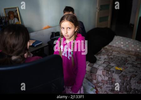 Oksana, la madre di Darina, 13 anni, e Arthur, 7 anni nei loro appartamenti al piano terra di un edificio in cui 20 persone vivono senza elettricità, acqua o gas. La famiglia è rifugiata dalla regione di Donbass, sono arrivati 2 anni fa ad Irpin per iniziare una nuova vita, non vogliono lasciare di nuovo la loro casa anche se c'è shelling tutto intorno a loro. Irpin centrale, come la città è sotto shelling durante l'invasione russa dell'Ucraina, il 11 marzo 2022. Foto di Raffaello Lafargue/ABACAPRESS.COM Foto Stock