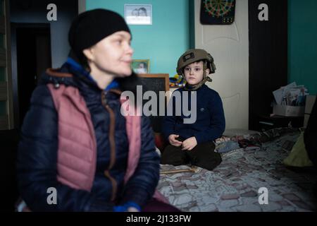 Oksana, la madre di Darina, 13 anni, e Arthur, 7 anni nei loro appartamenti al piano terra di un edificio in cui 20 persone vivono senza elettricità, acqua o gas. La famiglia è rifugiata dalla regione di Donbass, sono arrivati 2 anni fa ad Irpin per iniziare una nuova vita, non vogliono lasciare di nuovo la loro casa anche se c'è shelling tutto intorno a loro. Irpin centrale, come la città è sotto shelling durante l'invasione russa dell'Ucraina, il 11 marzo 2022. Foto di Raffaello Lafargue/ABACAPRESS.COM Foto Stock