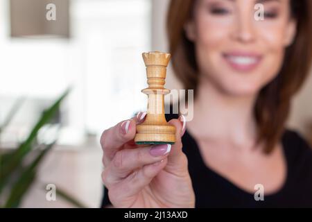 Felice giovane donna che tiene la regina degli scacchi, profondità di campo Foto Stock