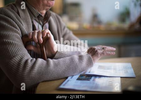 Primo piano di un uomo anziano che legge il giornale nel centro di cura della casa. Foto Stock