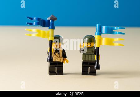 LEGO piccoli uomini con bandiere di Ucraina. Un uomo giocattolo minifattolo che regge una bandiera blu. Soldati mini figura. Sostegno del popolo ucraino. Ucraina, Kiev - 20 marzo 2022. Foto Stock