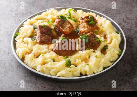 Greco Sofrito manzo brasato lento con sugo di carne piccante guarnito con purè di patate primo piano in un piatto sul tavolo. Orizzontale Foto Stock