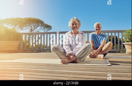 Mantenere una mente e un corpo sani. Shot di una coppia anziana che fa yoga insieme sul loro patio esterno. Foto Stock