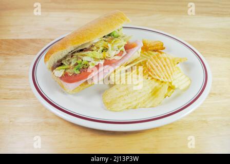 Un panino Sub con patatine servite come pranzo freddo Foto Stock