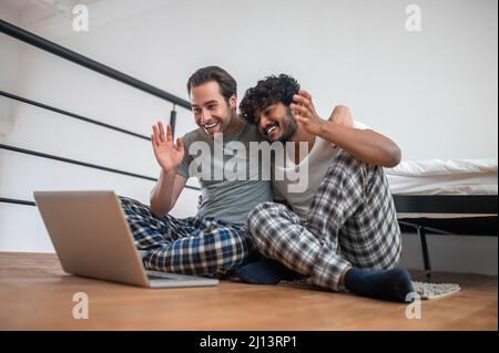 Allegro coppia biraciale che saluta qualcuno via Skype Foto Stock