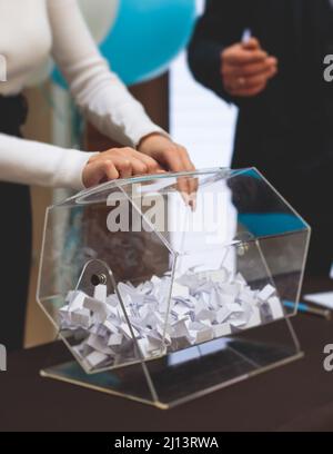 Processo di estrazione dei premi, estrazione di un numero vincente di lotteria macchina, tamburo di lotteria con bingo palle e vincita dei biglietti in occasione dell'evento con l'ospite e Foto Stock